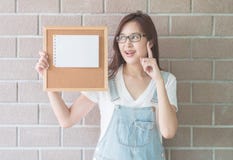 La femme asiatique avec le panneau de liège à disposition avec ont un visage d'idée photo stock La femme asiatique avec le panneau de liège à disposition avec ont un visage d'idée photo stock
