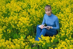 La femme dessine se reposer sur une herbe pendant la journée Elle peint se reposer sur un gisement de graine de colza photographie stock La femme dessine se reposer sur une herbe pendant la journée Elle peint se reposer sur un gisement de graine de colza photographie stock