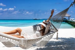 La femme détend dans un hamac sur une plage tropicale photographie stock La femme détend dans un hamac sur une plage tropicale photographie stock