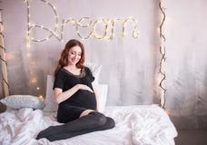 La femme enceinte avec de longs cheveux rouges, dans une robe noire image libre de droits La femme enceinte avec de longs cheveux rouges, dans une robe noire image libre de droits