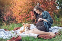 La femme enceinte avec un ventre s'assied sur une couverture et raconte des histoires au bébé Concept de grossesse et d'harmonie photo libre de droits La femme enceinte avec un ventre s'assied sur une couverture et raconte des histoires au bébé Concept de grossesse et d'harmonie photo libre de droits