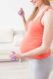 La femme enceinte mignonne s'exerce avec des poids photographie stock La femme enceinte mignonne s'exerce avec des poids photographie stock