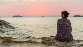 La femme enveloppée dans le plaid repose seul sur le voyage de côte photographie stock libre de droits La femme enveloppée dans le plaid repose seul sur le voyage de côte photographie stock libre de droits