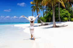La femme marche sur une plage tropicale avec le chapeau blanc photo stock La femme marche sur une plage tropicale avec le chapeau blanc photo stock