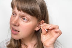 La femme nettoie ses oreilles sales avec le tampon de coton photographie stock libre de droits La femme nettoie ses oreilles sales avec le tampon de coton photographie stock libre de droits