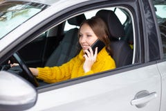 La femme parle ? son t?l?phone tout en conduisant une voiture photos stock La femme parle ? son t?l?phone tout en conduisant une voiture photos stock