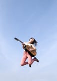 La femme sautant avec la guitare photographie stock La femme sautant avec la guitare photographie stock