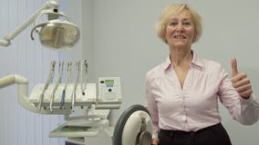 La femme supérieure montre son pouce au bureau de dentiste images libres de droits La femme supérieure montre son pouce au bureau de dentiste images libres de droits