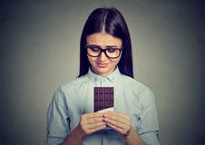 La femme triste a fatigué des restrictions de régime implorant la barre de chocolat de bonbons images stock La femme triste a fatigué des restrictions de régime implorant la barre de chocolat de bonbons images stock