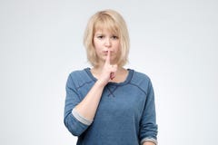 La femmina adorabile seria chiede di tenere le informazioni segrete confidenziali, vestito nel pulover blu fotografia stock La femmina adorabile seria chiede di tenere le informazioni segrete confidenziali, vestito nel pulover blu fotografia stock