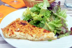 La fetta di quiche francese con insalata è servito su un piatto immagine stock libera da diritti La fetta di quiche francese con insalata è servito su un piatto immagine stock libera da diritti
