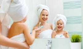 La figlia del bambino e della madre pulisce i loro denti con lo spazzolino da denti fotografia stock libera da diritti La figlia del bambino e della madre pulisce i loro denti con lo spazzolino da denti fotografia stock libera da diritti
