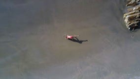 La figura de la muchacha que hace yoga llega a ser más pequeña en la antena de la playa La figura de la muchacha que hace yoga llega a ser más pequeña en la antena de la playa