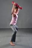 La fille d'adolescent faisant des exercices avec des haltères pour se développer avec des haltères muscles sur le fond gris Portr images stock La fille d'adolescent faisant des exercices avec des haltères pour se développer avec des haltères muscles sur le fond gris Portr images stock