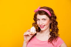 La fille dans la robe rose de style de la pin-up mange le gâteau avec de la crème photo stock La fille dans la robe rose de style de la pin-up mange le gâteau avec de la crème photo stock