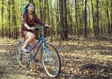 La fille dans la robe monte une bicyclette par la for?t photographie stock La fille dans la robe monte une bicyclette par la for?t photographie stock