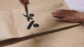 La fille dessine avec une brosse sur de diverses émotions de sacs en papier Le concept des émotions dans les smiley photos libres de droits La fille dessine avec une brosse sur de diverses émotions de sacs en papier Le concept des émotions dans les smiley photos libres de droits