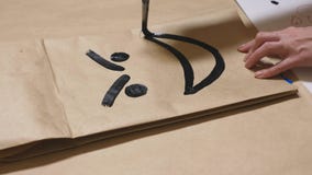 La fille dessine avec une brosse sur de diverses émotions de sacs en papier Le concept des émotions dans les smiley photo stock La fille dessine avec une brosse sur de diverses émotions de sacs en papier Le concept des émotions dans les smiley photo stock