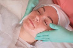 La fille passe par des traitements faciaux dans le salon de beauté Gants de port d'esthéticien appliquer la crème hydratante sur photo libre de droits La fille passe par des traitements faciaux dans le salon de beauté Gants de port d'esthéticien appliquer la crème hydratante sur photo libre de droits