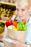 La fille remet le paquet avec la liste de lecture de légumes frais de produits photo stock La fille remet le paquet avec la liste de lecture de légumes frais de produits photo stock