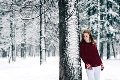 La fille s'est habillée dans un chandail marron et le pantalon blanc s'est penché contre le tronc d'arbre contre un contexte de l photos stock La fille s'est habillée dans un chandail marron et le pantalon blanc s'est penché contre le tronc d'arbre contre un contexte de l photos stock