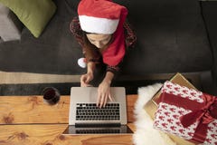 La fille seule dans un chapeau de Noël faisant des emplettes en ligne, utilise un ordinateur portable image stock La fille seule dans un chapeau de Noël faisant des emplettes en ligne, utilise un ordinateur portable image stock