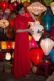 La fille vietnamienne dans la robe rouge vend des lanternes de Chinois de souvenir Photographie stock libre de droits La fille vietnamienne dans la robe rouge vend des lanternes de Chinois de souvenir Photographie stock libre de droits