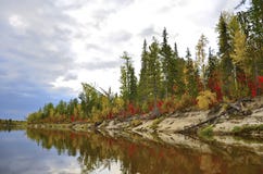 La foresta variopinta di autunno è riflessa nel fiume contro il cielo blu fotografie stock La foresta variopinta di autunno è riflessa nel fiume contro il cielo blu fotografie stock