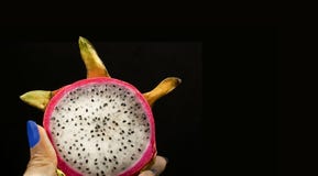 La fruta del dragón en un fondo negro se corta en la mano imagenes de archivo La fruta del dragón en un fondo negro se corta en la mano imagenes de archivo