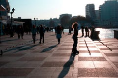 La gente camina a lo largo de la 'promenade' en la ciudad del mar en la puesta del sol fotografía de archivo La gente camina a lo largo de la 'promenade' en la ciudad del mar en la puesta del sol fotografía de archivo