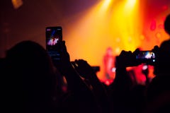 La gente che guarda un concerto e qualcuno foto e video della fucilazione con un cellulare fotografia stock libera da diritti La gente che guarda un concerto e qualcuno foto e video della fucilazione con un cellulare fotografia stock libera da diritti