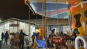 La gente del carrusel de los paseos del niño camina en parque con las atracciones La gente del carrusel de los paseos del niño camina en parque con las atracciones