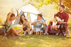 La gente joven goza en la música de tambores y de la guitarra en acampada fotografía de archivo La gente joven goza en la música de tambores y de la guitarra en acampada fotografía de archivo