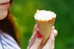 La giovane bella ragazza con capelli scorrenti lunghi mangia il gelato giorno luminoso pieno di sole fotografie stock libere da diritti La giovane bella ragazza con capelli scorrenti lunghi mangia il gelato giorno luminoso pieno di sole fotografie stock libere da diritti