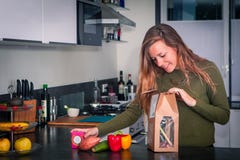 La giovane donna apre un pacchetto degli ingredienti freschi per fare una cena sana fotografie stock libere da diritti La giovane donna apre un pacchetto degli ingredienti freschi per fare una cena sana fotografie stock libere da diritti