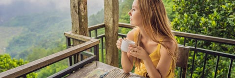 La giovane donna beve il caffè in un caffè nell'INSEGNA delle montagne, FORMATO LUNGO immagini stock libere da diritti La giovane donna beve il caffè in un caffè nell'INSEGNA delle montagne, FORMATO LUNGO immagini stock libere da diritti