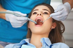 La giovane donna che ottiene i suoi denti ha controllato da un dentista fotografie stock La giovane donna che ottiene i suoi denti ha controllato da un dentista fotografie stock