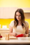La giovane donna che prepara insalata a casa in cucina fotografia stock libera da diritti La giovane donna che prepara insalata a casa in cucina fotografia stock libera da diritti