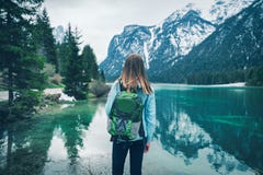 La giovane donna con lo zaino verde sta stando sul lago immagine stock libera da diritti La giovane donna con lo zaino verde sta stando sul lago immagine stock libera da diritti