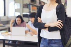 La giovane donna dell'Asia, armi dello studente di college ha attraversato con la borsa di scuola o immagine stock La giovane donna dell'Asia, armi dello studente di college ha attraversato con la borsa di scuola o immagine stock
