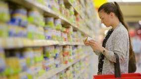 La giovane donna sceglie gli alimenti per bambini nel supermercato, madre sceglie l'alimento per il loro bambino nel mercato, sup stock footage La giovane donna sceglie gli alimenti per bambini nel supermercato, madre sceglie l'alimento per il loro bambino nel mercato, sup stock footage