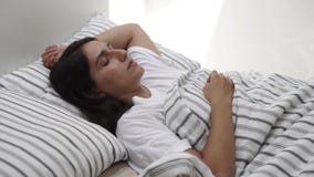 La giovane donna si trova a letto con gli occhi chiusi, signora sta dormendo stock footage La giovane donna si trova a letto con gli occhi chiusi, signora sta dormendo stock footage