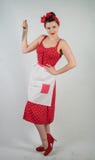 La goupille dangereuse vers le haut de la femme au foyer de fille dans la robe rouge de point de polka de cru se tient avec un co image stock La goupille dangereuse vers le haut de la femme au foyer de fille dans la robe rouge de point de polka de cru se tient avec un co image stock