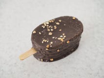 La grande crème glacée sur un bâton couvert du chocolat est sur la table photo libre de droits La grande crème glacée sur un bâton couvert du chocolat est sur la table photo libre de droits