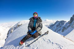 La grimpeuse de femme dans le casque et veste avec des bâtons de trekking s'assied sur une montagne photo libre de droits La grimpeuse de femme dans le casque et veste avec des bâtons de trekking s'assied sur une montagne photo libre de droits