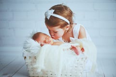 La hermana de los niños besa al bebé soñoliento recién nacido del hermano en una luz Foto de archivo libre de regalías La hermana de los niños besa al bebé soñoliento recién nacido del hermano en una luz Foto de archivo libre de regalías