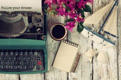 La imagen de la máquina de escribir del vintage con frase sigue sus sueños, cuaderno en blanco, taza de café y velero viejo La imagen de la máquina de escribir del vintage con frase sigue sus sueños, cuaderno en blanco, taza de café y velero viejo
