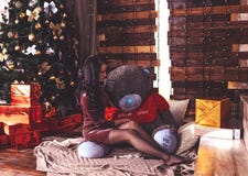 La jeune belle fille dans une robe pourpre brillante se tient prêt l'arbre de nouvelle année avec des décorations et des cadeaux photo libre de droits La jeune belle fille dans une robe pourpre brillante se tient prêt l'arbre de nouvelle année avec des décorations et des cadeaux photo libre de droits