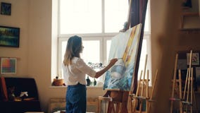 La jeune dame de peintre professionnel peint le paysage marin avec les peintures acryliques dépeignant les vagues marines de bate clips vidéos La jeune dame de peintre professionnel peint le paysage marin avec les peintures acryliques dépeignant les vagues marines de bate clips vidéos