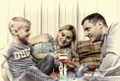 La jeune famille heureuse avec l'enfant se repose à la maison sur le divan photographie stock La jeune famille heureuse avec l'enfant se repose à la maison sur le divan photographie stock